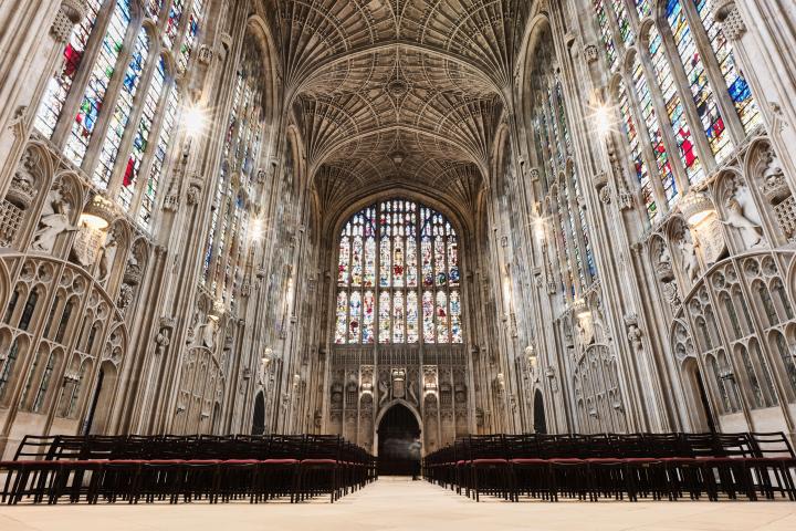 Interior of ornate Gothic chapel with vaulted ceiling and stained glass windows.