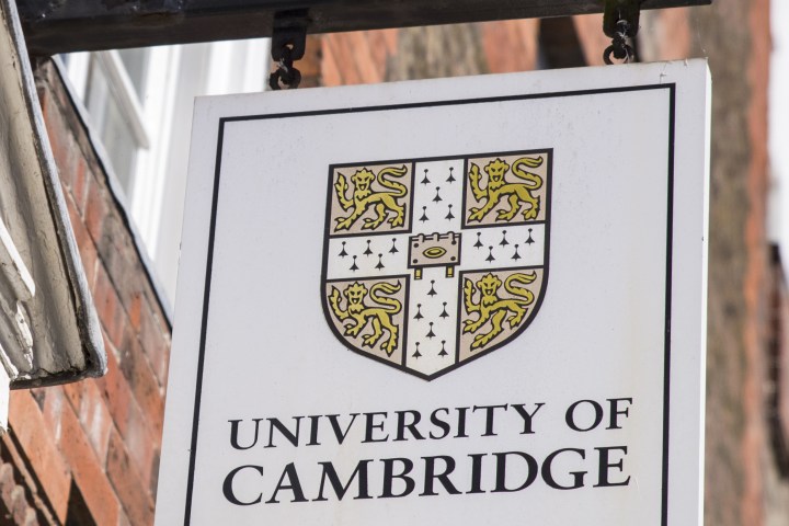 Sign with University of Cambridge crest and text on a brick wall.