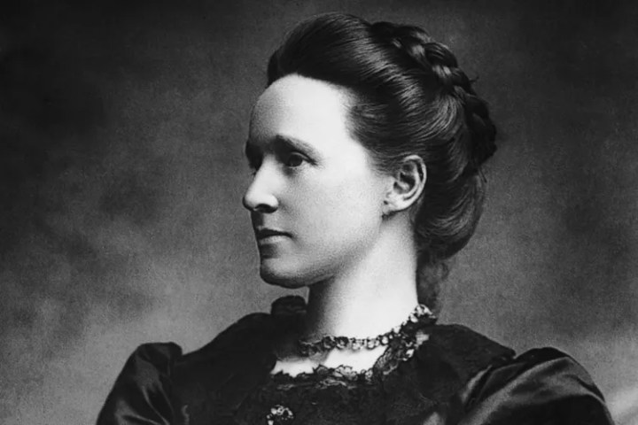 Black and white portrait of a woman with braided hair, wearing a dark dress.
